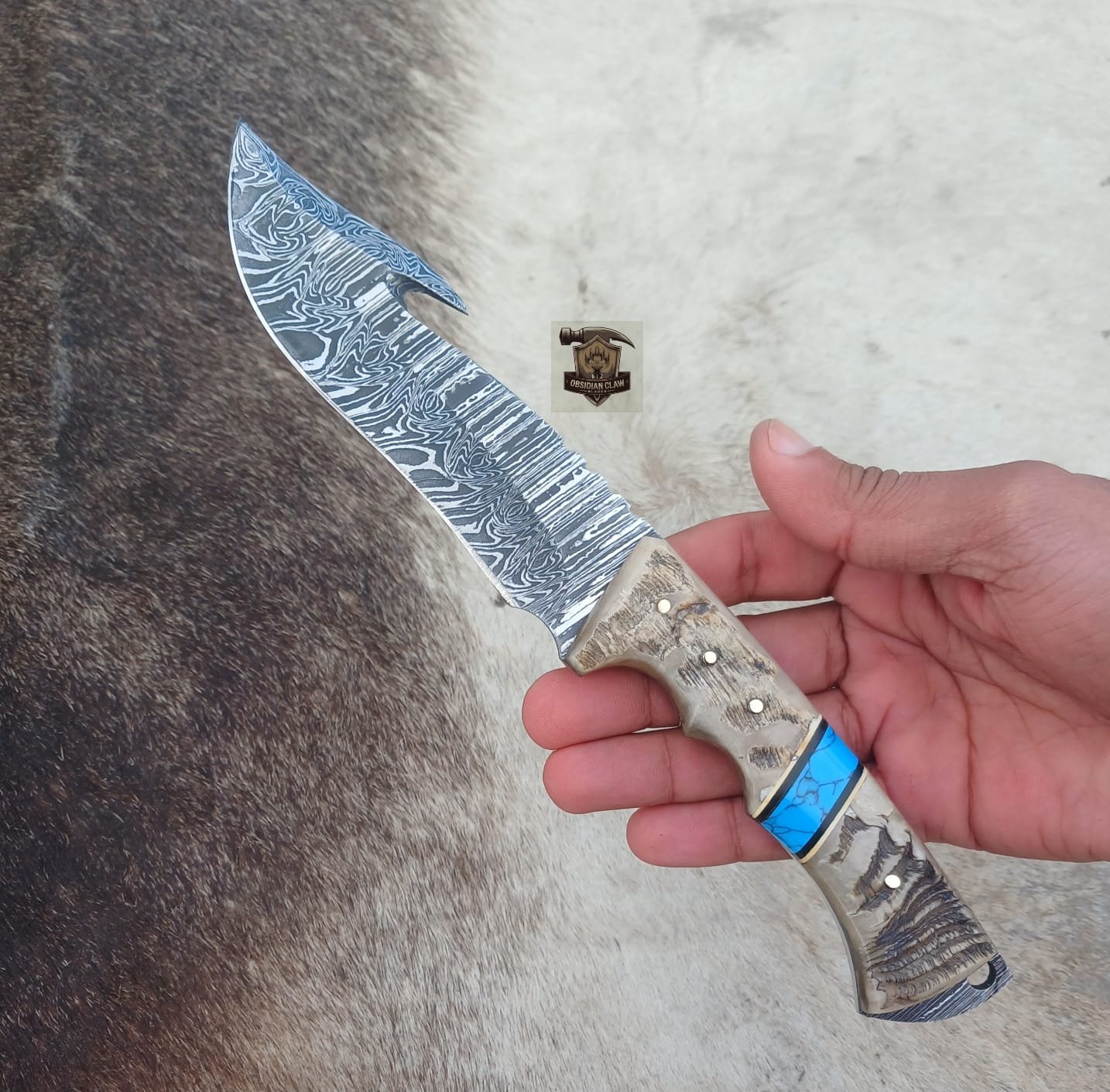 Handmade Damascus steel gut hook knife with leather sheath.
